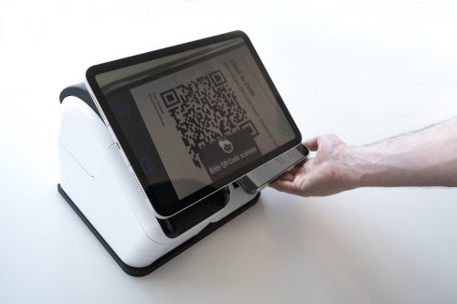 The guest holds the QR code in the marked position below the check-in station.